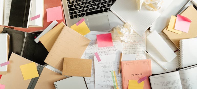 A pile of papers and documents in front of a laptop.