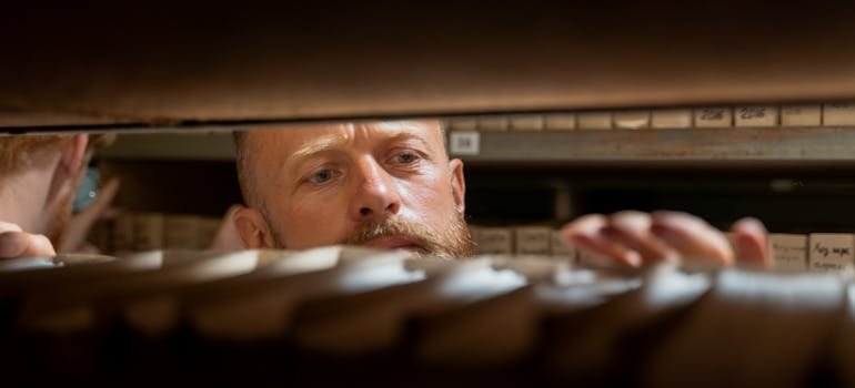 A man looking at the files on a shelf.