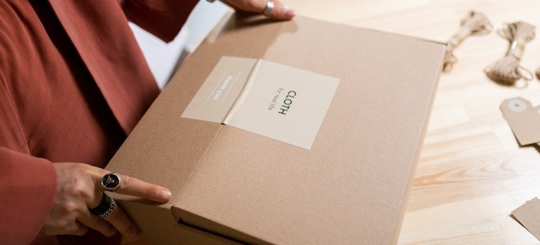 A person packing some items in a cardboard box.