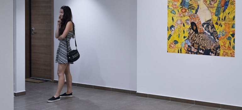 A woman standing near a painting.