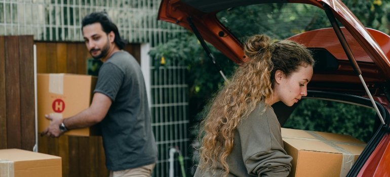 A couple carrying cardboard boxes while moving in after buying an apartment in the Bronx.