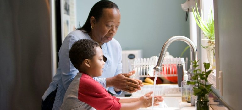 A mother and a child washing their hands and talking about how important it is to prevent clutter after moving/