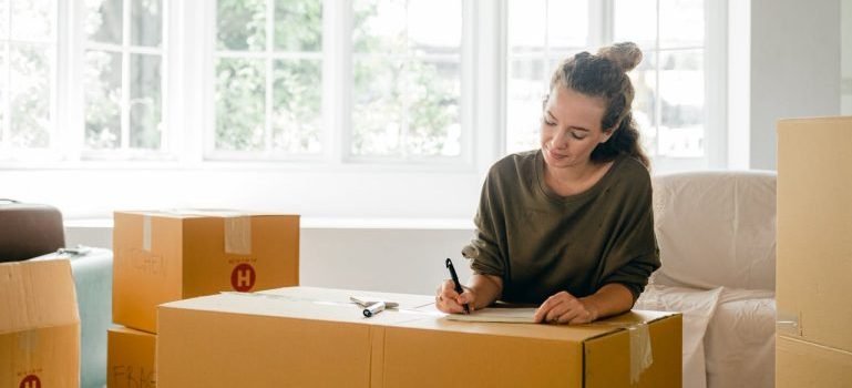 A woman labeling a box after creating a storage inventory