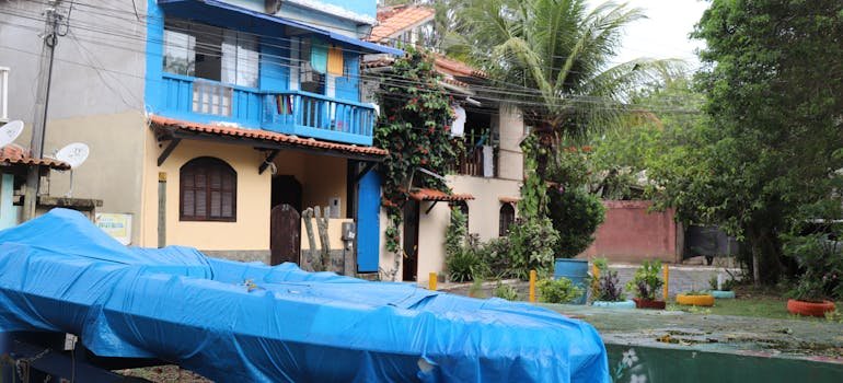 A boat in a yard covered with a blue cover.