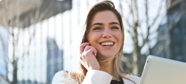A happy person holding a laptop and speaking on the phone.