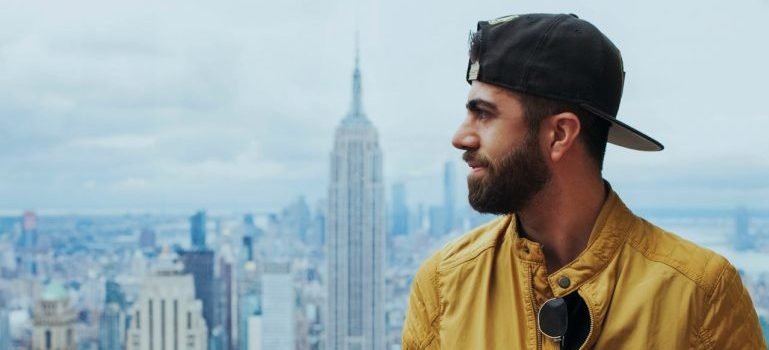 A man in a yellow jacket observing the NYC cityscape and thinking about how to build social connections after moving to the Bronx.