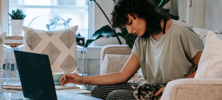 a woman sitting on the couch and reading about packing your pet terrarium on a laptop