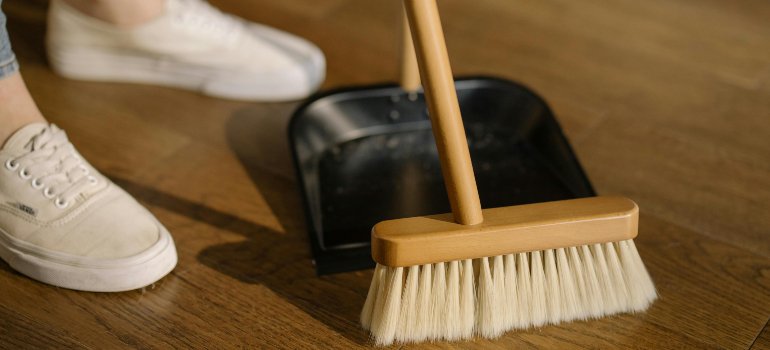 A broom and dustpan used for cleaning before preparing items for long-term storage.