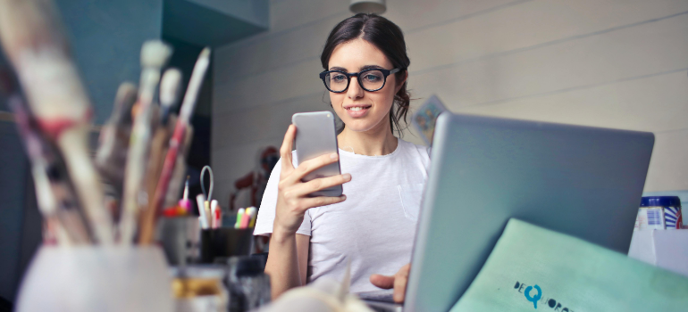 A woman in her office looking at her mobile phone.