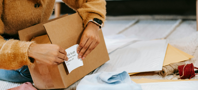 A person labeling a cardboard box.