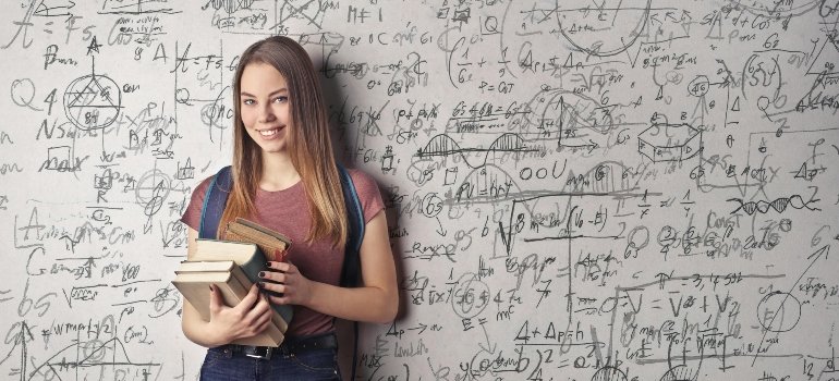 A girl holding her books and thinking about what every student should do before moving to campus.