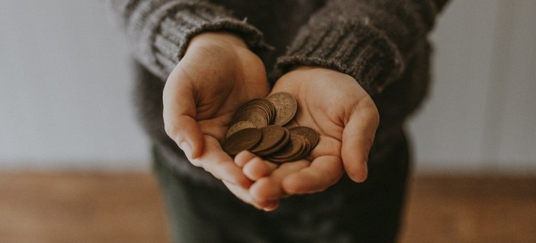 Person holding coins symbolizing the money you need to see fun activities in Manhattan and Brooklyn.