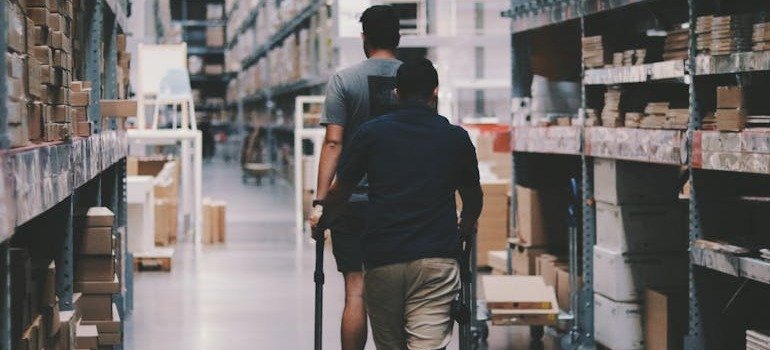 Two men putting a cart of items into a warehouse after discovering essential qualities renters seek in a storage unit in NYC