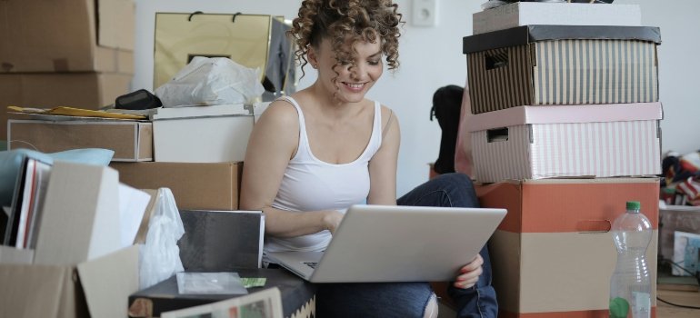 Woman using a laptop on the floor o find out why we accumulate so much in small apartments.