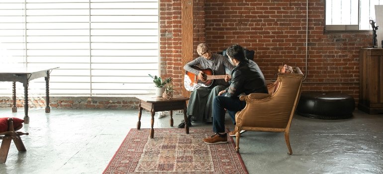 People sitting and playing the guitar.