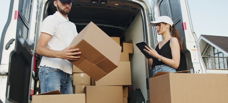 A man and a woman are working together on the delivery of boxes.