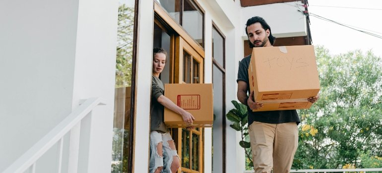 Two people moving boxes from a house after learning how to avoid fines when moving in NYC.