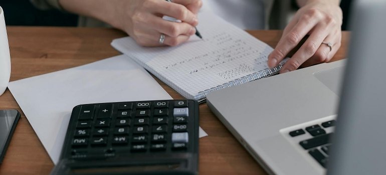 A person calculates costs in a notebook before renting storage in other boroughs.