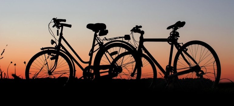 Two bicycles in the foreground and the sunset in the background.