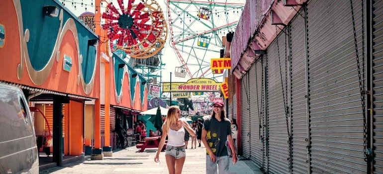 A couple is walking in the carnival in New York and talking about sticking to your budget in an expensive city.