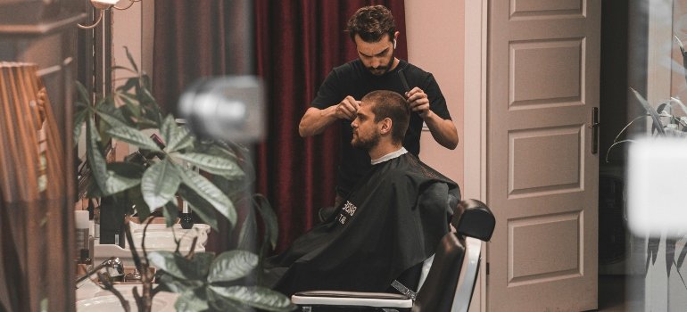 Man receiving a haircut at a Staten Island barber shop as haircuts add to the monthly expenses in Staten Island.