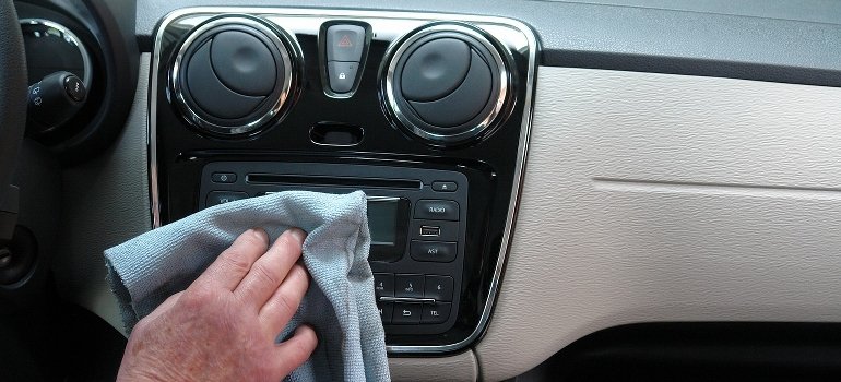 A person is cleaning a car interior with a cloth.