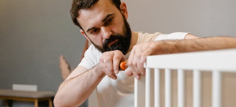 A man helping you disassemble a crib before you store your baby gear between kids.
