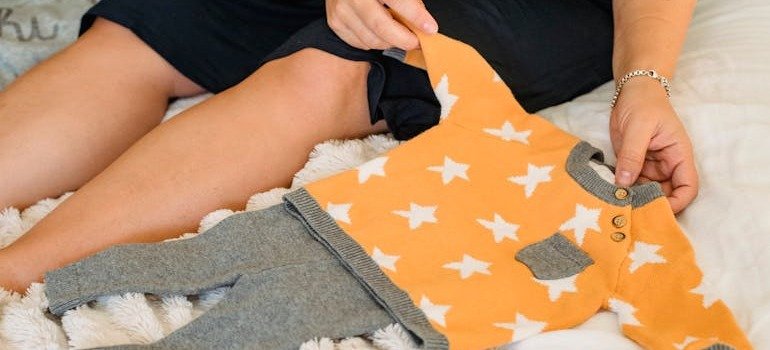 A person folding baby clothes.
