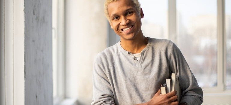 A student holding a book and smiling.
