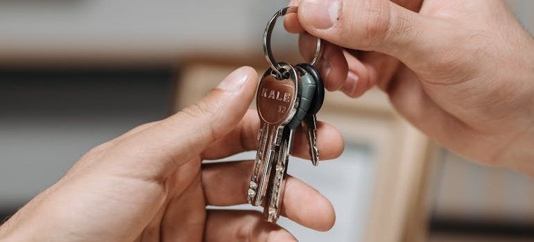 One person giving keys to another person after finding an apartment in Brooklyn as a student.