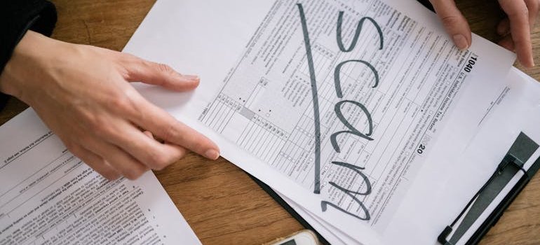 A person looking at some documents with the word "scam" written on them.