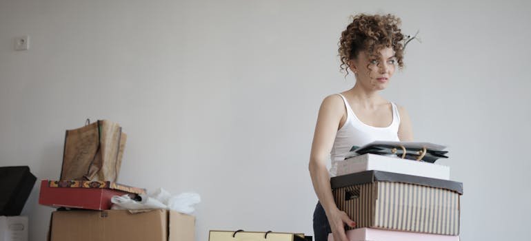A young woman carrying the boxes after finding out how self-storage in NYC can simplify apartment subletting.