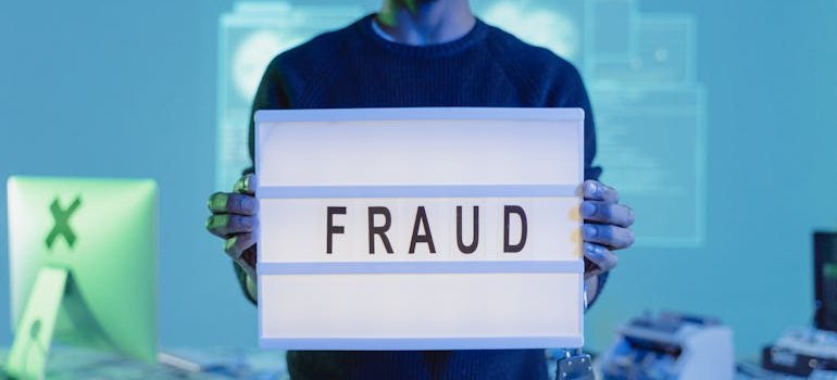 A person holding a sign with the word "FRAUD" on it.