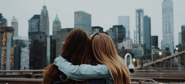 Two friends hugging and looking at the NYC skyline
