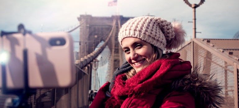 A woman taking a picture by the Brooklyn Bridge as part of Gen Z-friendly living in NYC