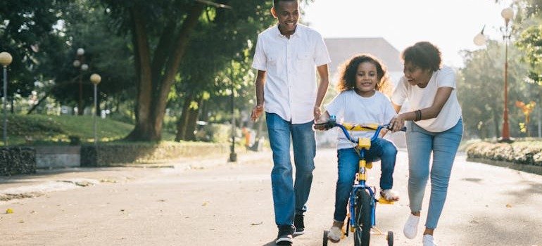 Parents teaching their child to ride a bike.