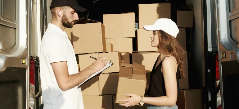 A delivery worker and customer discussing storage options with boxes loaded onto a van.