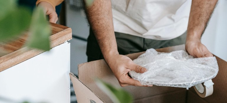 Two people putting plates into a box.