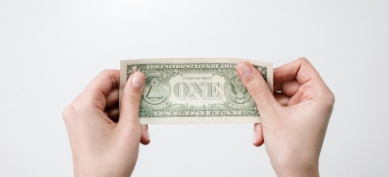 A person holding a one dollar banknote.