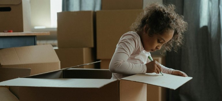 A child drawing inside a cardboard box.