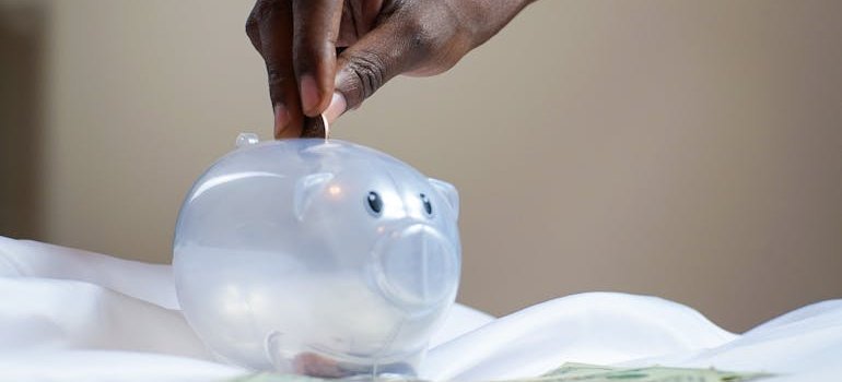 A person putting a coin into a piggy bank.
