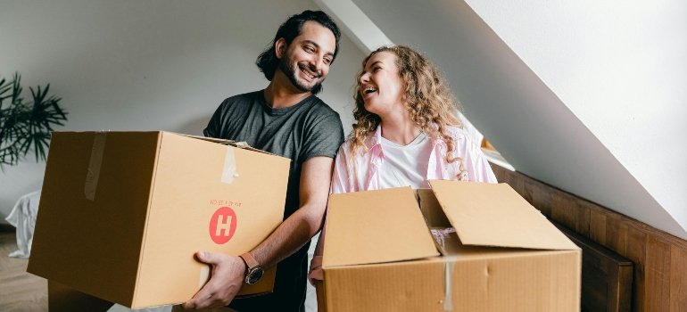 A happy couple carrying moving boxes after opting for the convenience of storage in NYC for different uses.