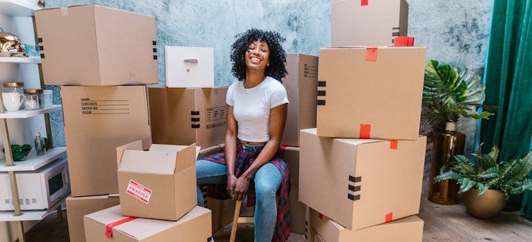 A person sitting on a chair surrounded with cardboard boxes.