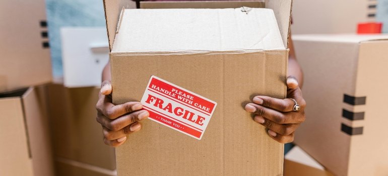A person holding a fragile-labeled box, highlighting the importance of affordable storage costs in Manhattan and NYC’s surrounding areas.