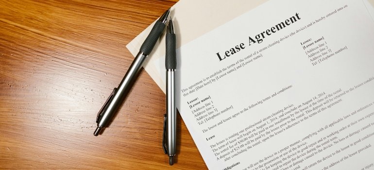 Lease papers on a wooden surface with two pens nearby.