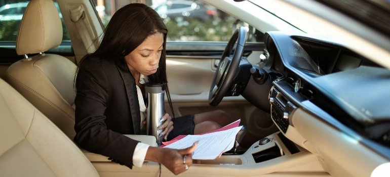 A professional studies a file labeled vehicle storage laws and regulations in a vehicle.