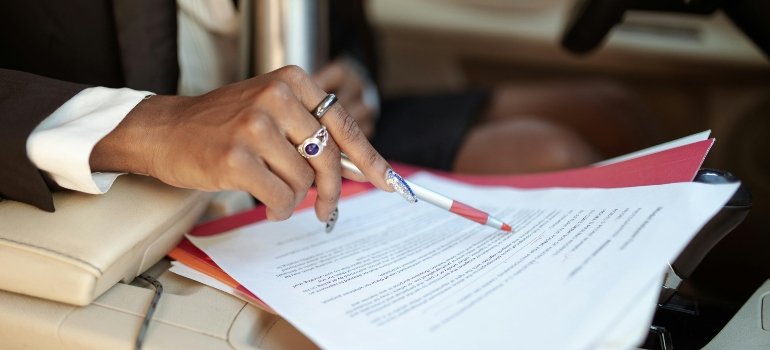 Close view of a person with a red pen marking details in vehicle storage laws and regulations.