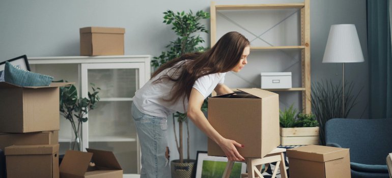 A woman packing up a room while thinking of a packing order for storage.