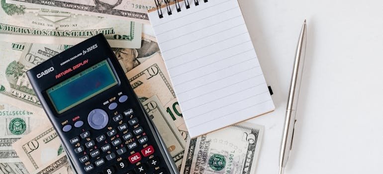 A calculator on top of dollar bills ready to calculate the cost of setting up a remote office in the Bronx.