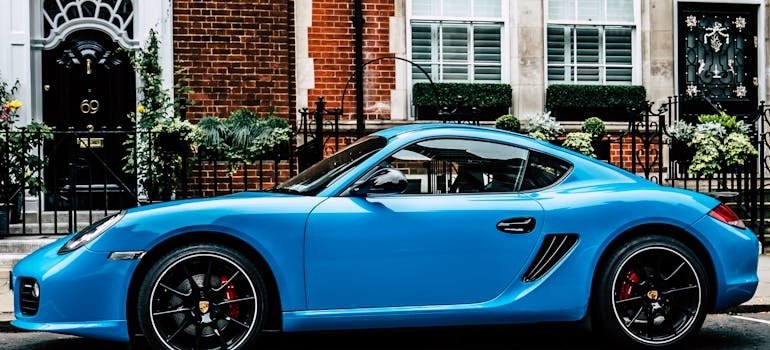 Blue car in front of a Manhattan apartment.